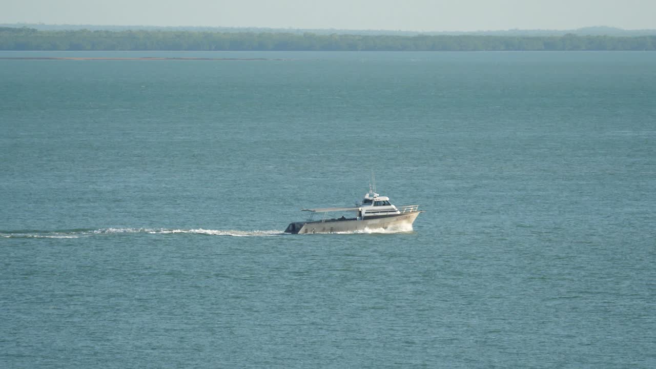 Modern aluminium fishing - diving boat crosses tropical harbour Left to Right