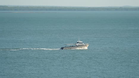modern aluminium fishing - diving boat crosses tropical harbour left to right
