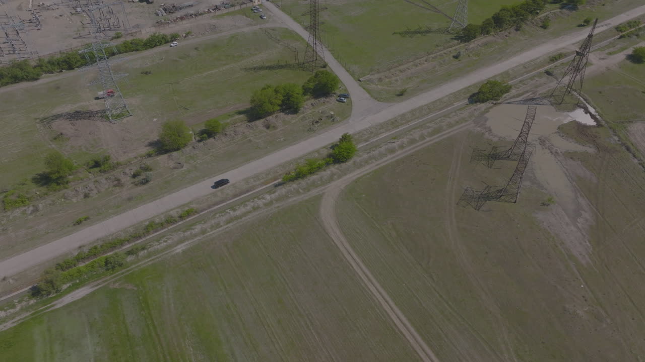 toma de seguimiento aéreo de un todoterreno negro en una carretera junto a una planta de energía