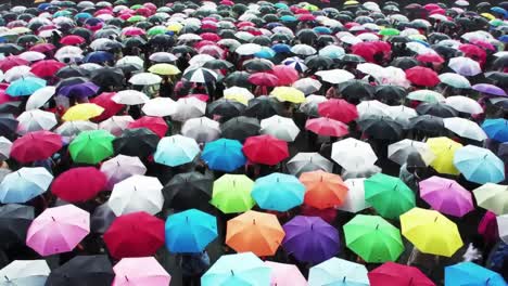 a stunning aerial view of a vibrant crowd sheltered under colorful umbrellas, capturing the essence of unity and diversity in a rainy atmosphere