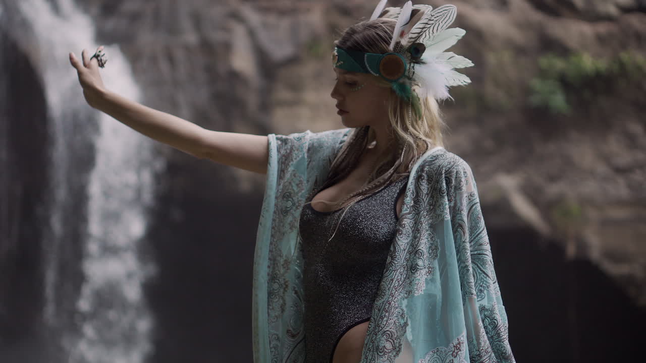 Woman in Feather Headdress by Waterfall