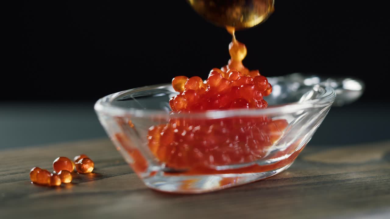 Raccogliere caviale rosso fresco in una ciotola di vetro