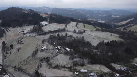 A-flight-over-the-countryside-with-a-path-leading-through-the-trees-and-a-view-of-the-surrounding-thing-during-the-beginning-of-the-snowfall