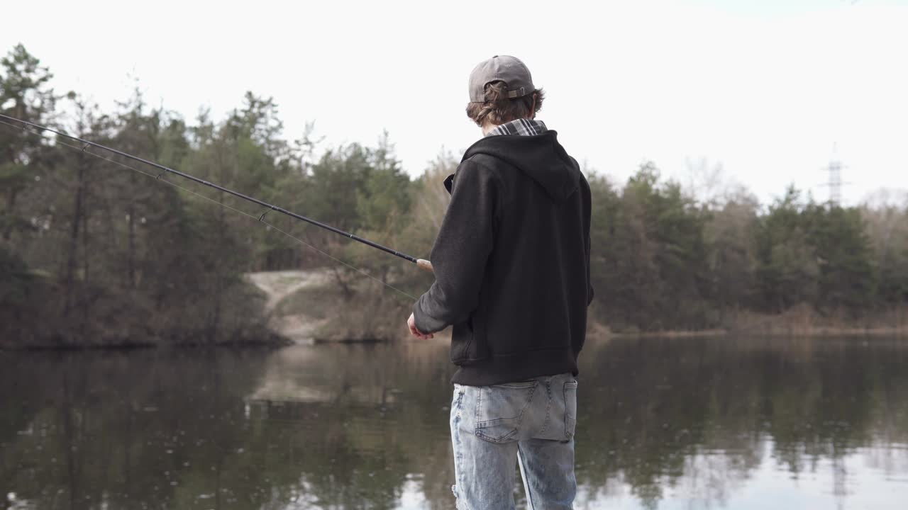 Seorang pemuda menangkap ikan predator dengan teknik spinning dari tepi. Memancing sebagai hobi