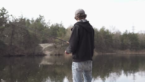 a young guy catches a predatory fish on spinning from the shore. fishing as a hobby.