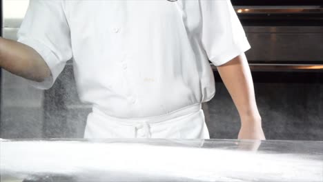 slow motion video of spreading flour over the table before preparation of bread in a bakery shop