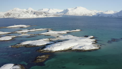 vista aérea de pequeñas islas cubiertas de nieve en el océano ártico con un hermoso paisaje invernal en el fondo