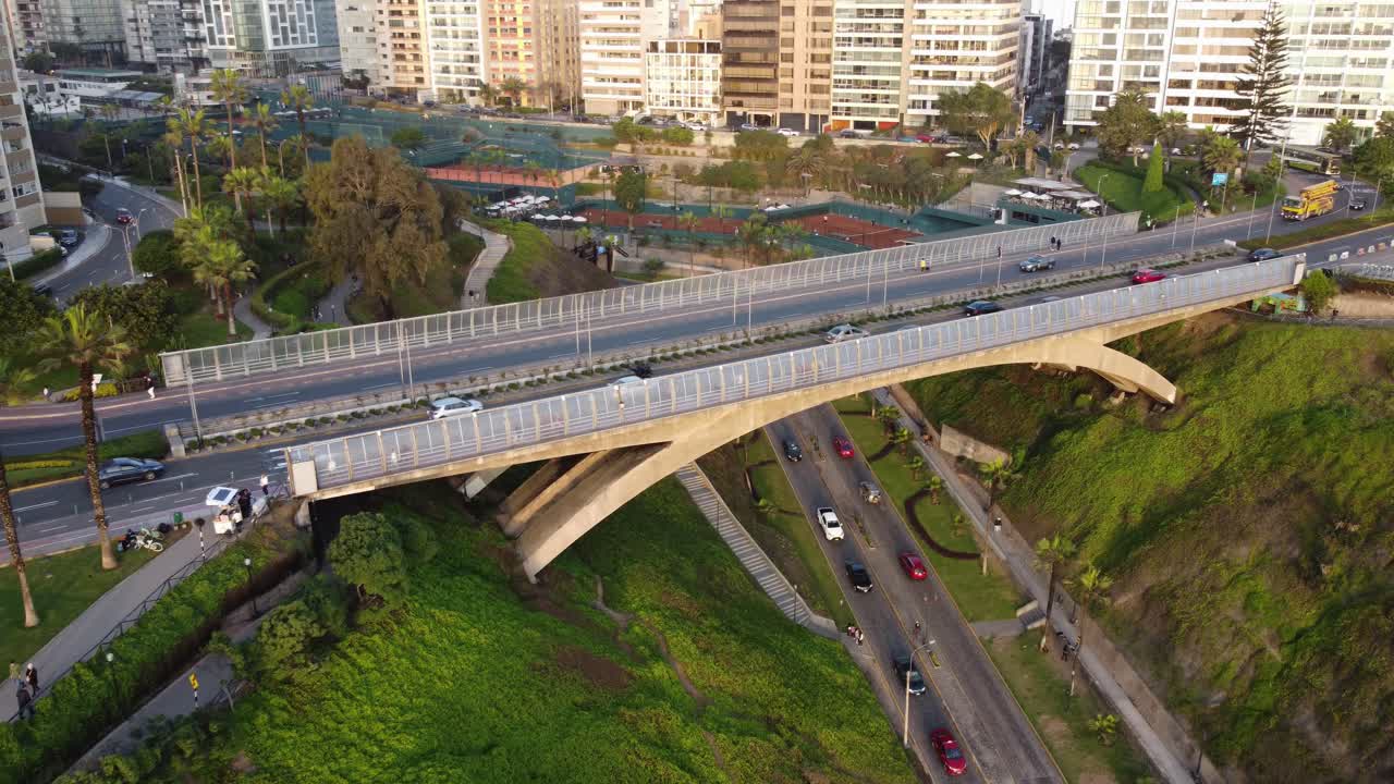 drone 4k de un puente con autos conduciendo sobre él, otra calle debajo del puente entre verdes colinas cubiertas de hierba