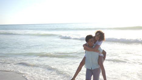 biracial couple enjoys a playful moment on a sunny beach with copy space