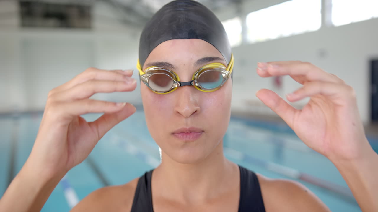 Adjusting swimming goggles, woman preparing for swim training at indoor pool