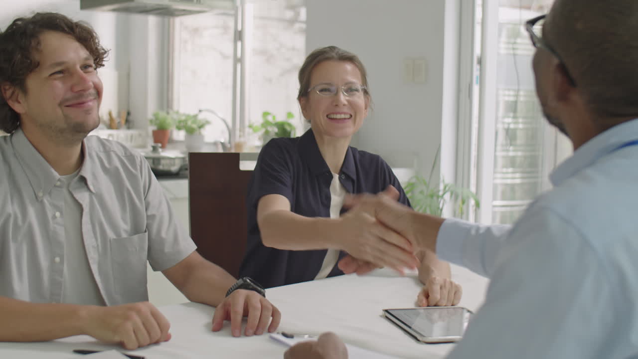 Couple and Sales Representative Signing Contract and Shaking Hands