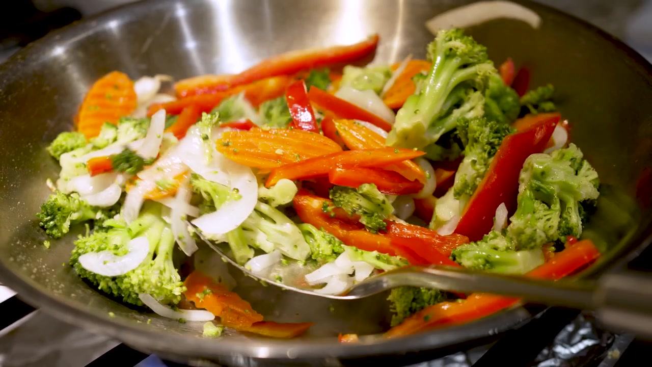 Spatola che salta le verdure in un wok.