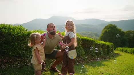 father and daughters playing with bubbles in a tea plantation