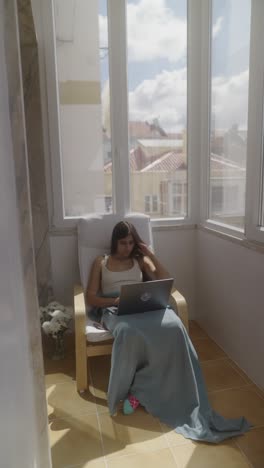 young woman working on laptop on a balcony