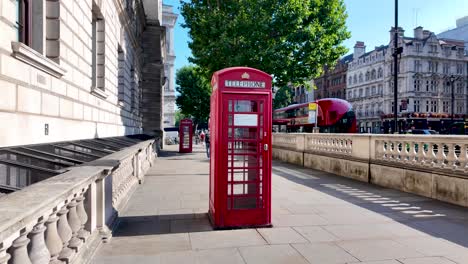 iconic red telephone booths and a double-decker bus on a sunny london street