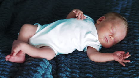 adorable peaceful sleeping newborn. little kid in white bodysuit lying on the blanket. close up.