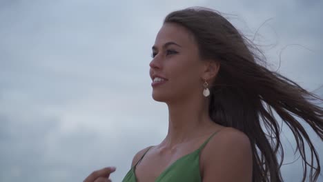 dark haired women with wild confident eyes smiling posing into camera portrait while wind blowing through her hair