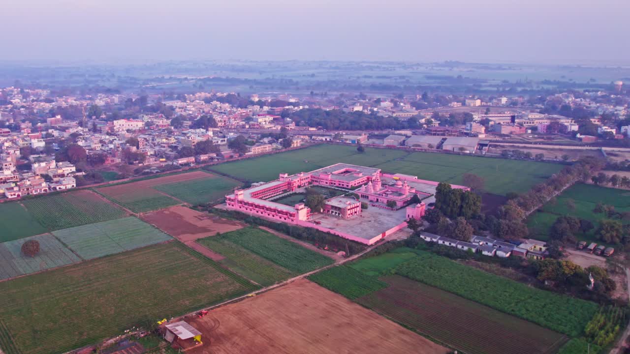 Aerial view of SHRI UDASIN SANGAT RISHI ASHRAM with agricultural land and sky at Ranopali Village, Ayodhya, uttar pradesh, india. day time, semi orbit, drone shot, 4k.