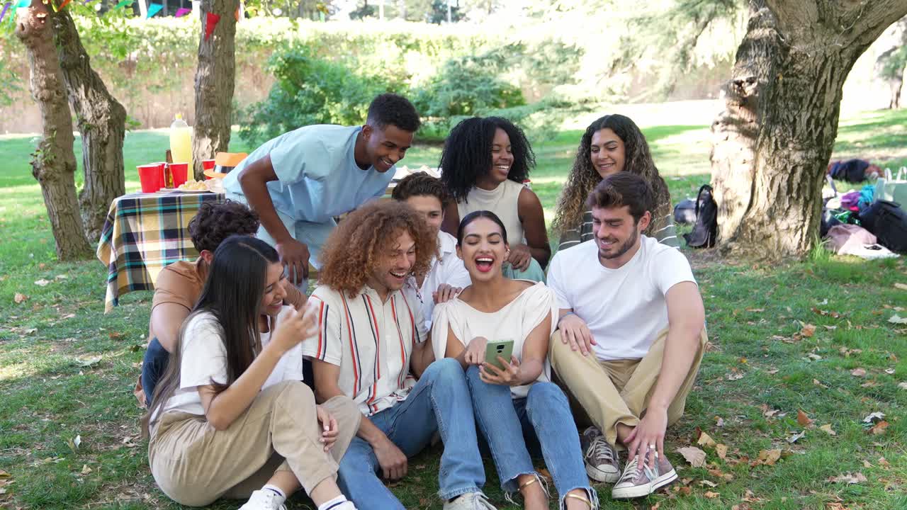 Gruppe af unge mennesker nyder en picnic i parken