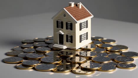 miniature house on a pile of coins