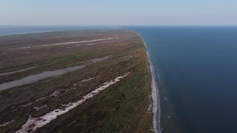 Aerial-melancholic-view-of-the-Danube-Delta-and-Black-Sea-meeting-in-the-wild-habitat-of-Gura-Portitei,-Romania,-Europe