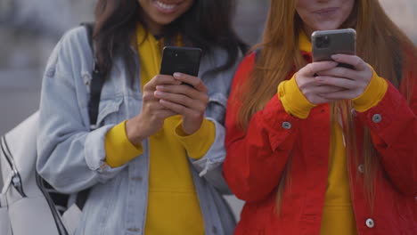 amigas felices multiétnicas que usan teléfonos inteligentes