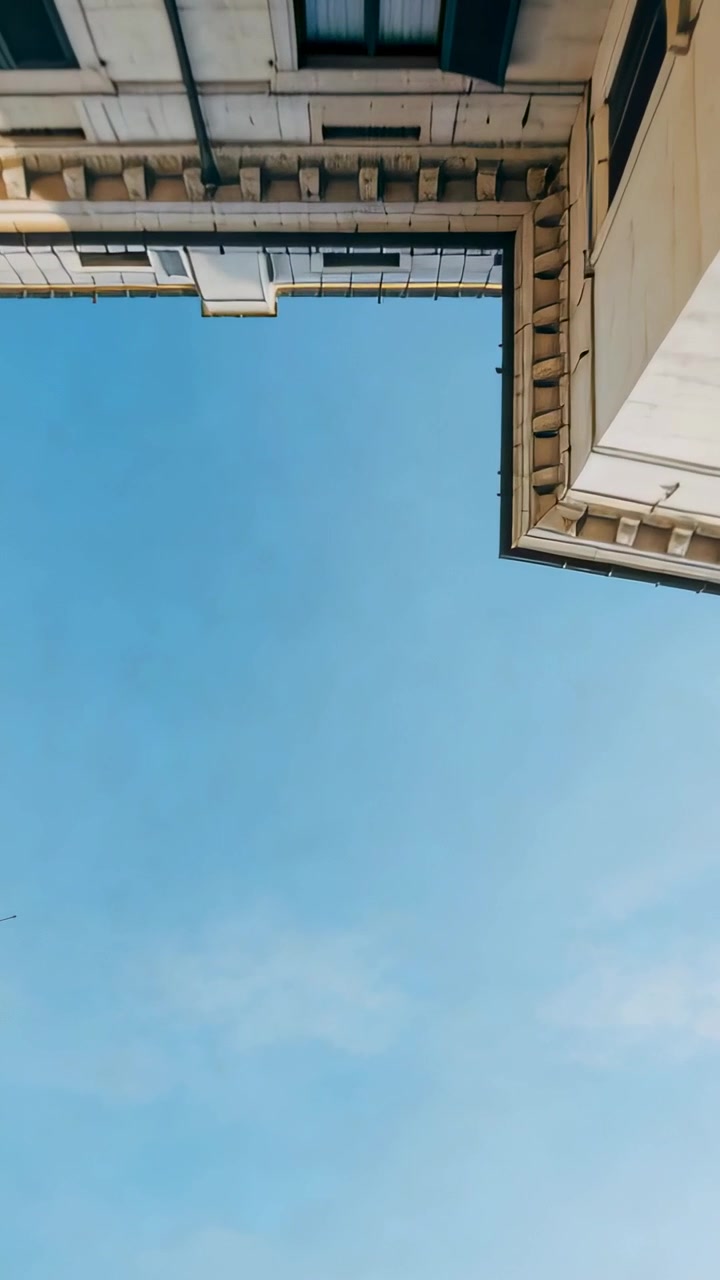 Video verticale: Inclinando la telecamera si rivela un cielo blu sempre più ampio nel cavedio per evidenziare le facciate incorniciate.