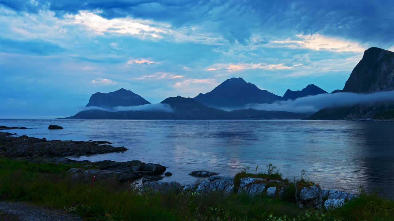 Panning Time Lapse. Mountains and sea fog. Norwegian coastal view on a cloudy blue summer night. Lofoten, Norway