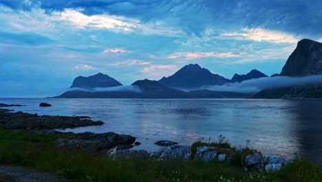 panning time lapse. mountains and sea fog. norwegian coastal view on a cloudy blue summer night. lofoten, norway