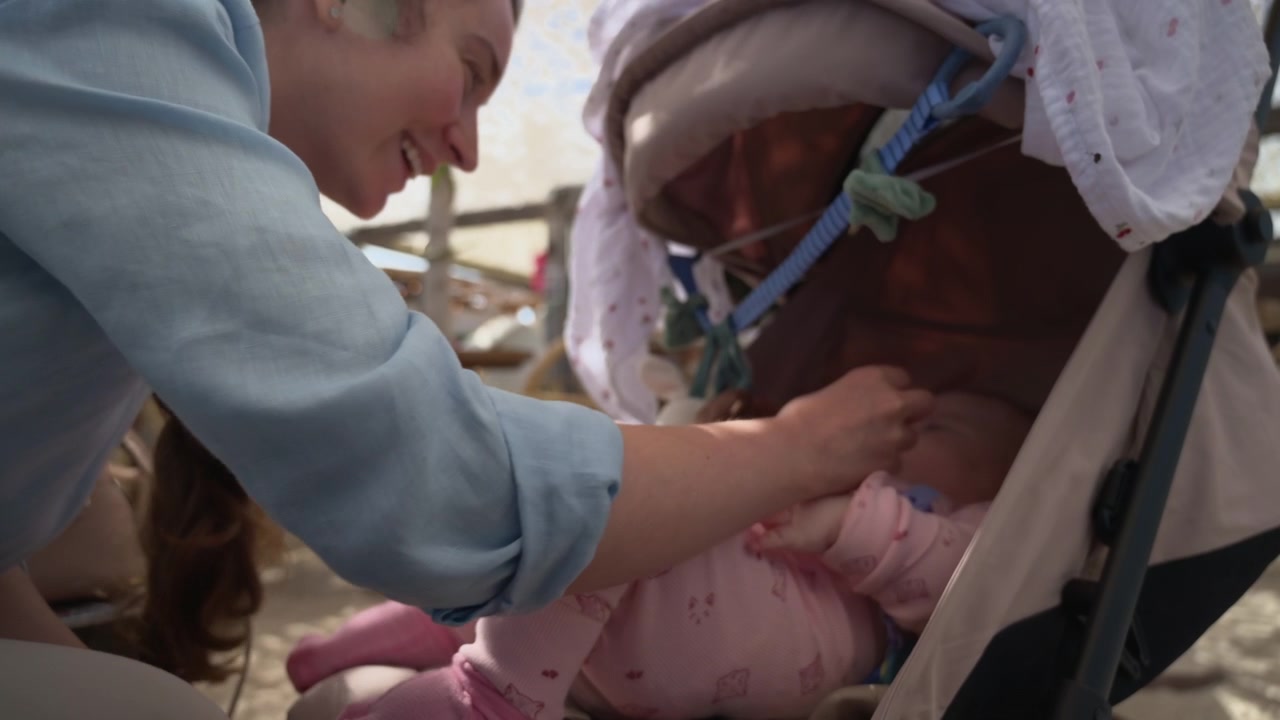 Bambino in passeggino in un lido con giocattoli appesi sopra