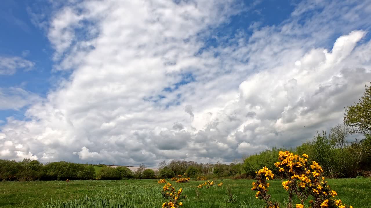 Time lapse of beautiful white clouds passing over sky and creating moving shadows on the meadow