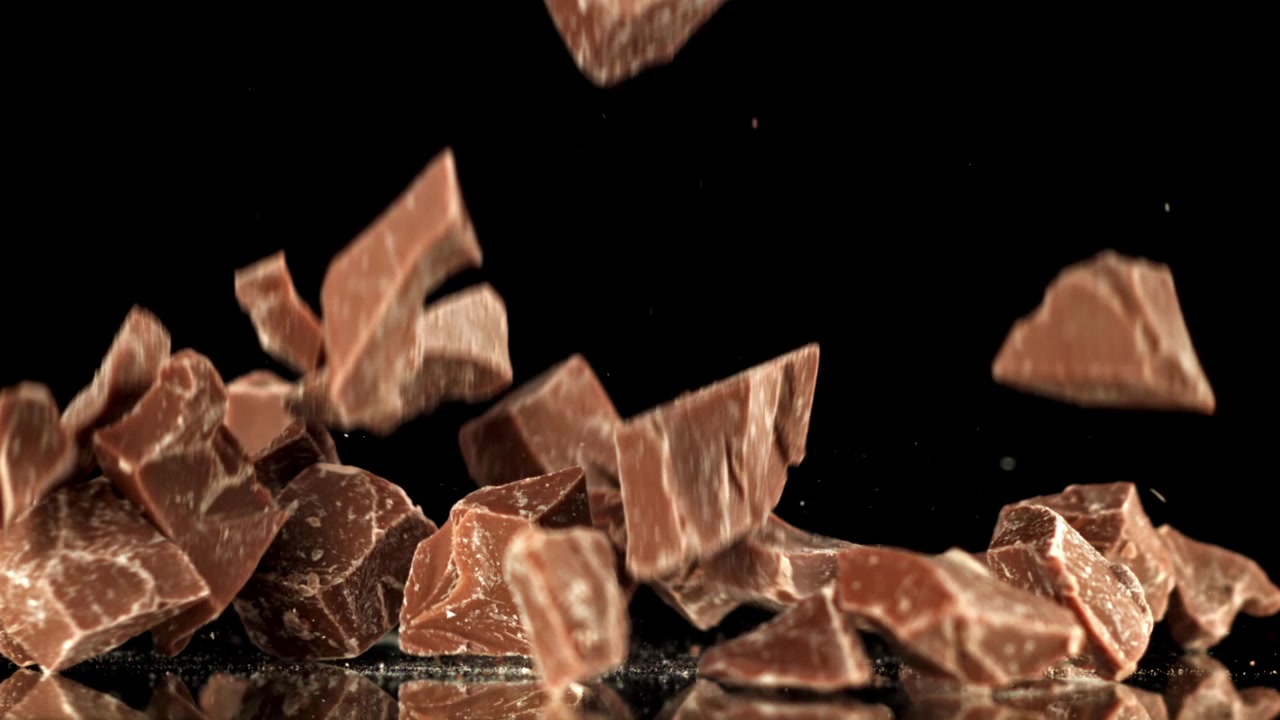 Pezzi di cioccolato che cadono al rallentatore su sfondo nero
