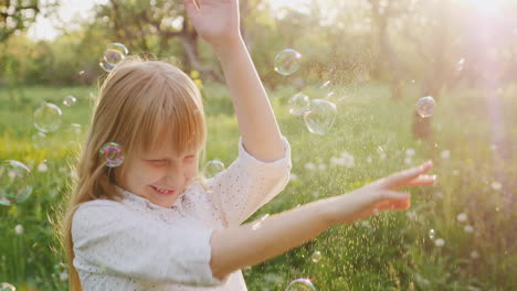 blonde girl is fun catching soap bubbles carefree happy child slow motion video