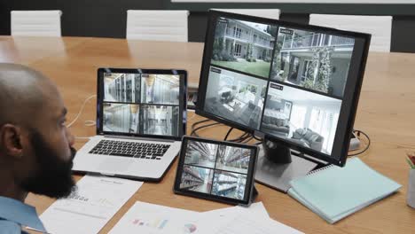 oficial de seguridad afroamericano viendo las vistas de las cámaras de cctv en pantallas de computadora, cámara lenta