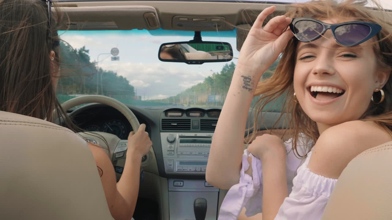 dos mujeres disfrutando de un viaje por carretera en un descapotable
