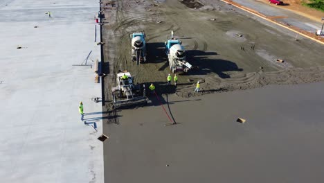 a screed machine smooths concrete while a supervisor observes