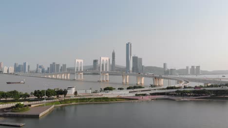 drone approach shot of traffic crossing sai van bridge in macau with mainland china skyscrapers in background