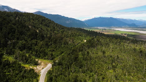 Overhead-aerial-drone-shot-over-mountain-range-with-a-winding-road-along-the-slope-in-Blue-Pools,-New-Zealand-at-daytime