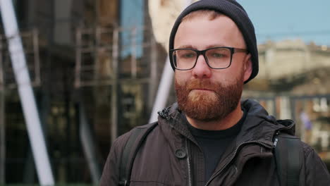 close-up portrait of a pensive bearded man in glasses and beanie