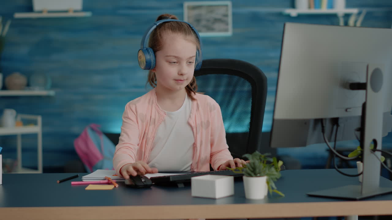 Young child wearing headphones and drawing on textbook