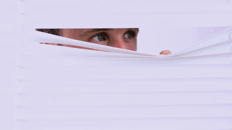 businessman peering through roller blind