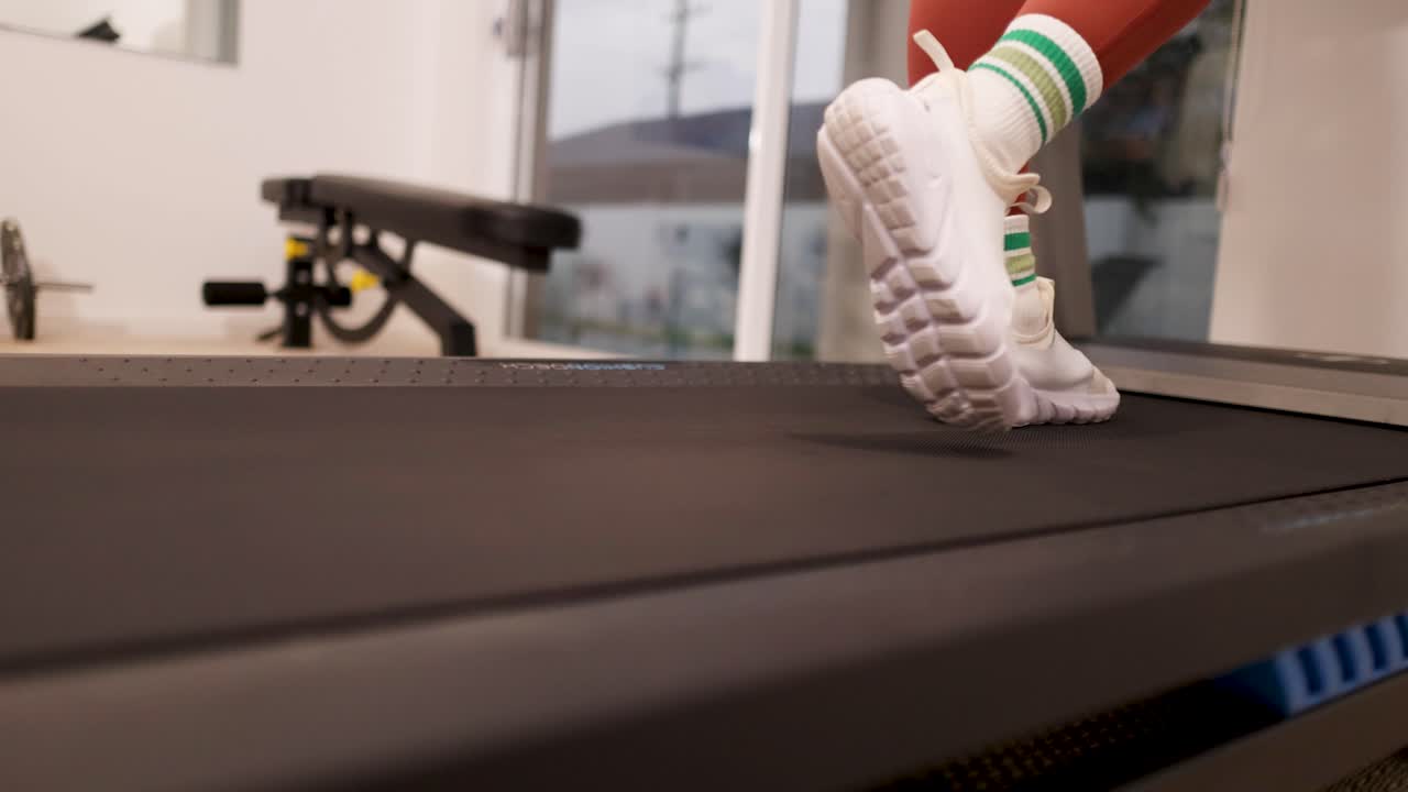 A woman exercises on a treadmill at home in Gold Coast, Australia. The video captures her feet in motion, emphasizing fitness