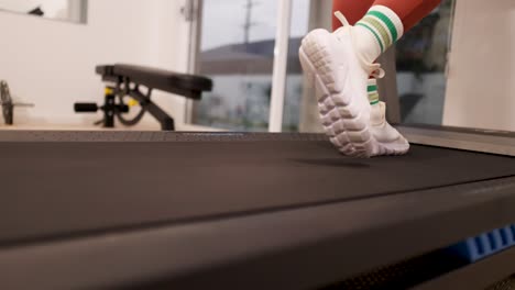 a woman exercises on a treadmill at home in gold coast, australia. the video captures her feet in motion, emphasizing fitness