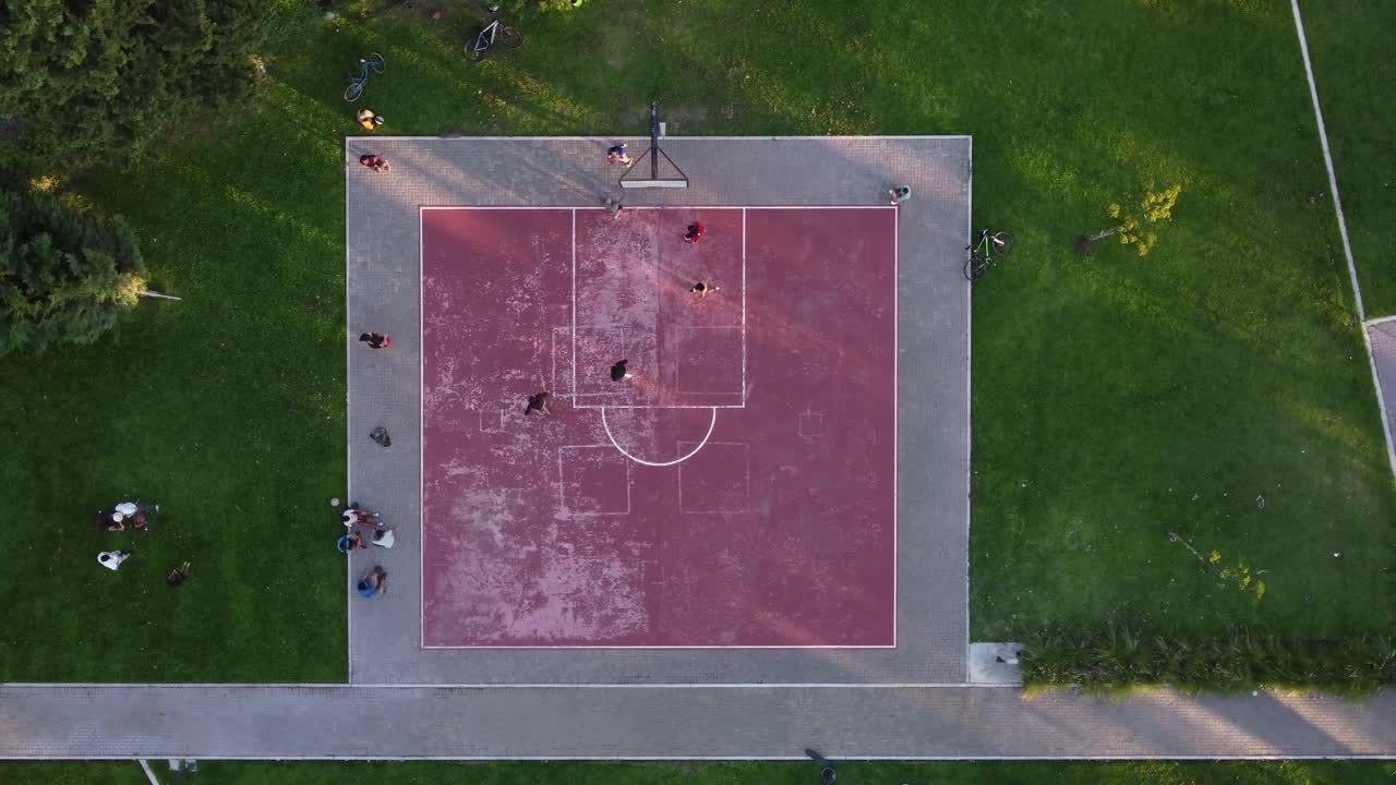 вид сверху вниз по кругу прямо над розовой общественной баскетбольной площадкой с игроками в окружении зелени, буэнос-айрес в аргентине
