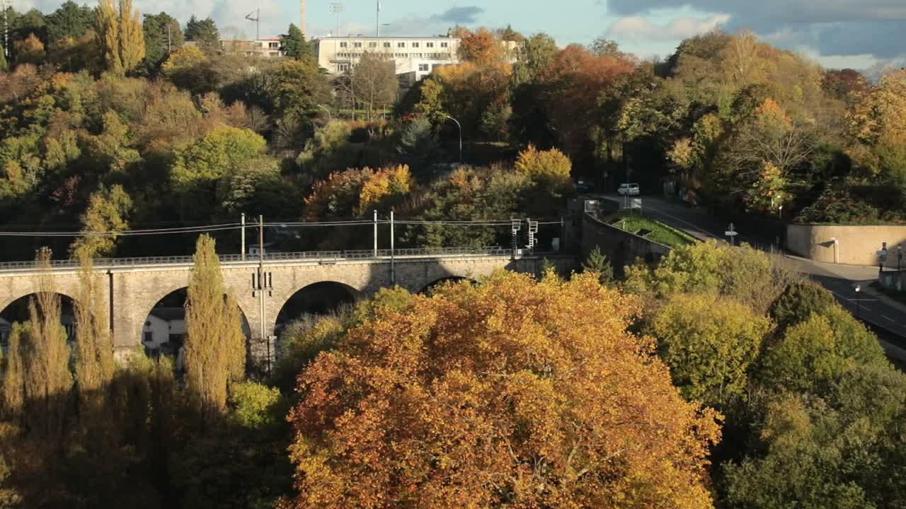 Efterårstræer og en historisk viadukt på en solskinsdag i et naturskønt landskab