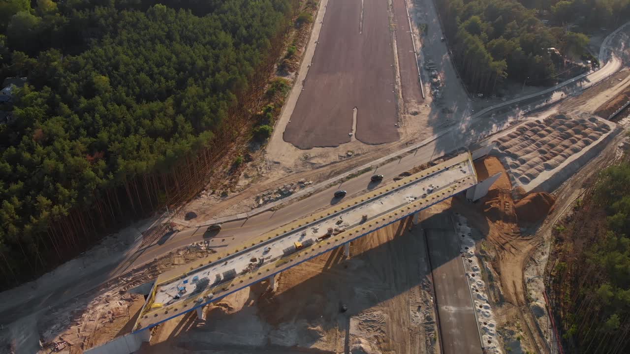 Aerial fly over modern road construction site with cars passing by