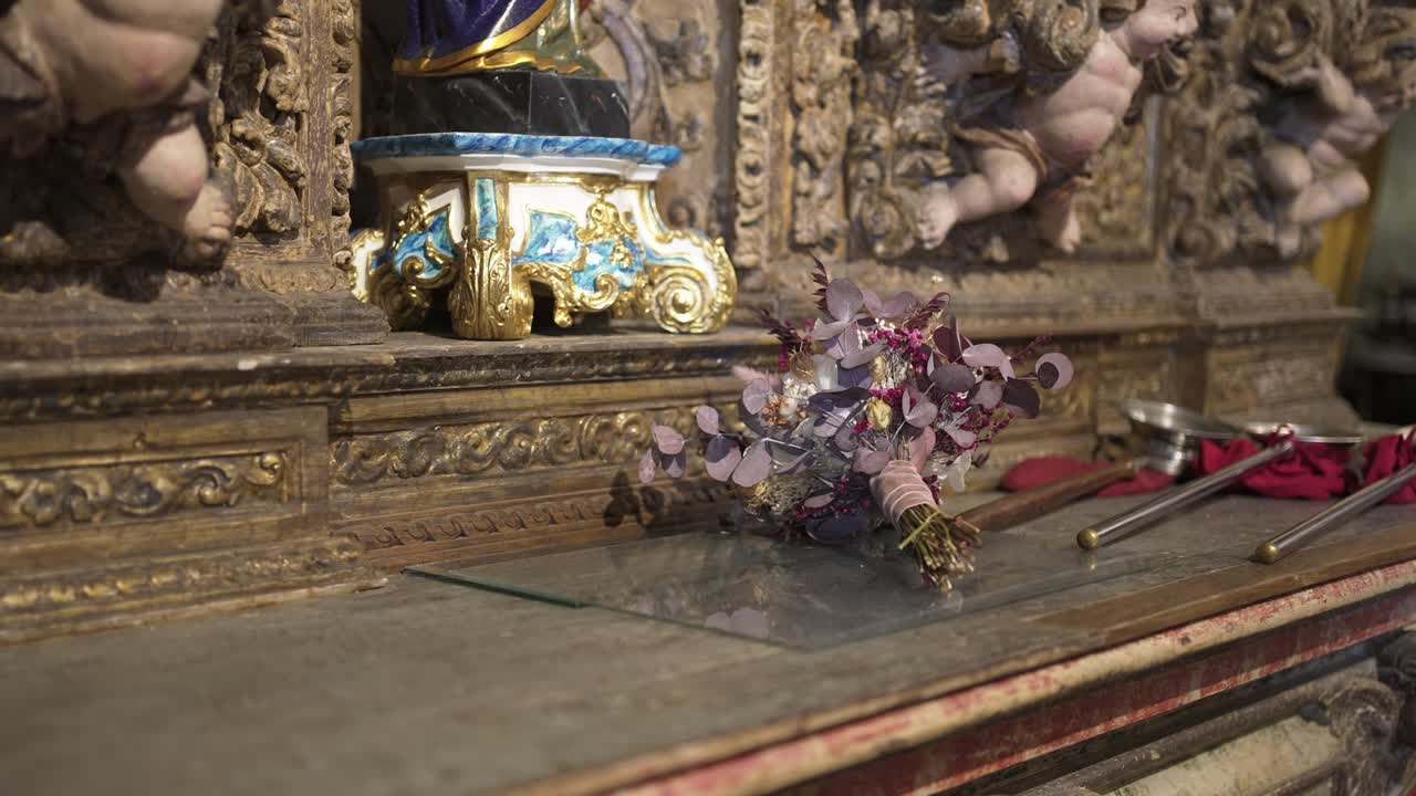Floral bouquet and ceremonial tools arranged on an intricately decorated altar