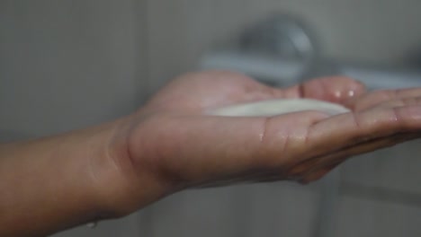 close-up of a woman's hand as she squirts shampoo into her hand during a shower