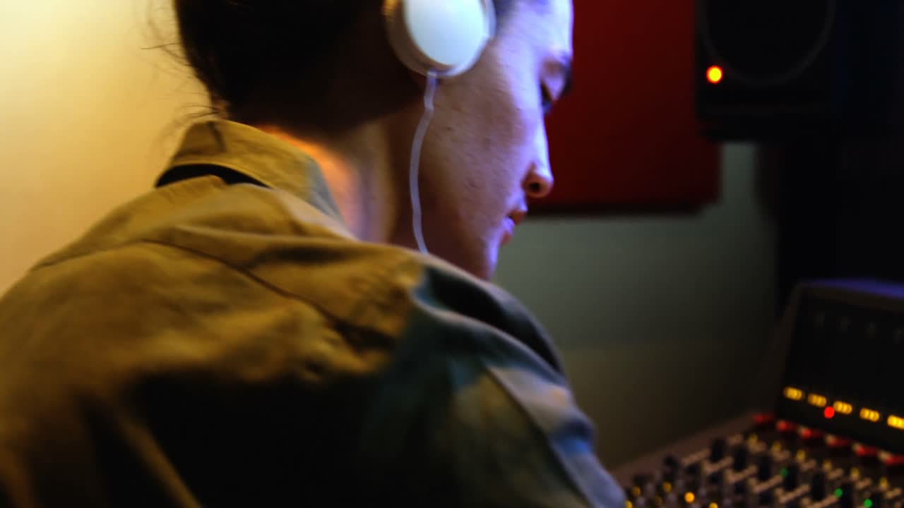 남성 오디오 엔지니어 가 음향 을  ⁇ 는 동안 헤드폰 을 듣고 있다