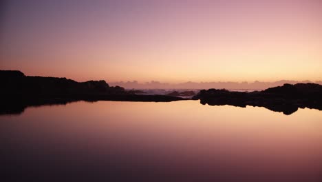 Statische-Symmetrische-Aufnahme-Von-Lebhaftem-Lila,-Gelbem-Sonnenaufgang,-Der-Sich-Im-Felsenbecken-Widerspiegelt